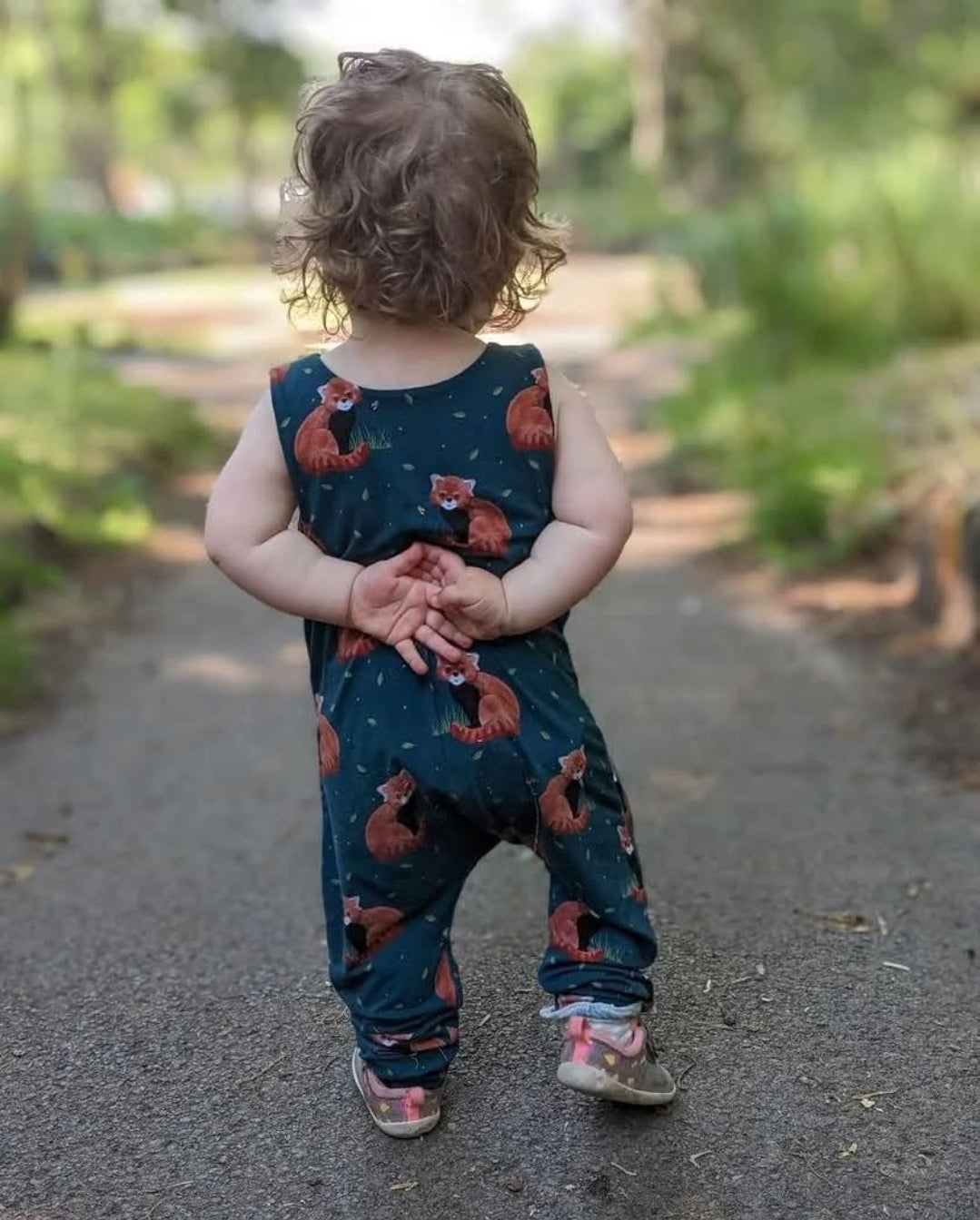 Happy baby wearing a handmade organic cotton romper, gentle on sensitive skin and sustainably made in the UK.